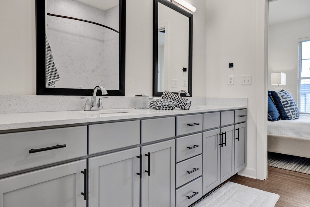 Modern bathroom with double vanity, gray cabinets, quartz countertops, and designer plank flooring at West Row Lofts and Townhomes in Birmingham, AL.